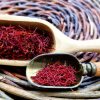 Dried Persian saffron threads in wooden and metal scoops on a woven mat